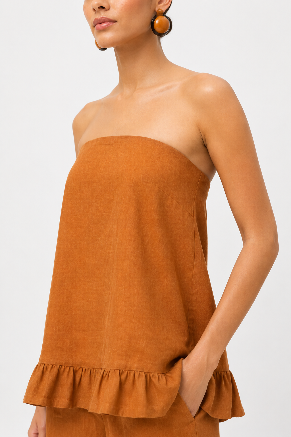 Close-up of Meher rust linen top showing natural linen texture and strapless neckline
