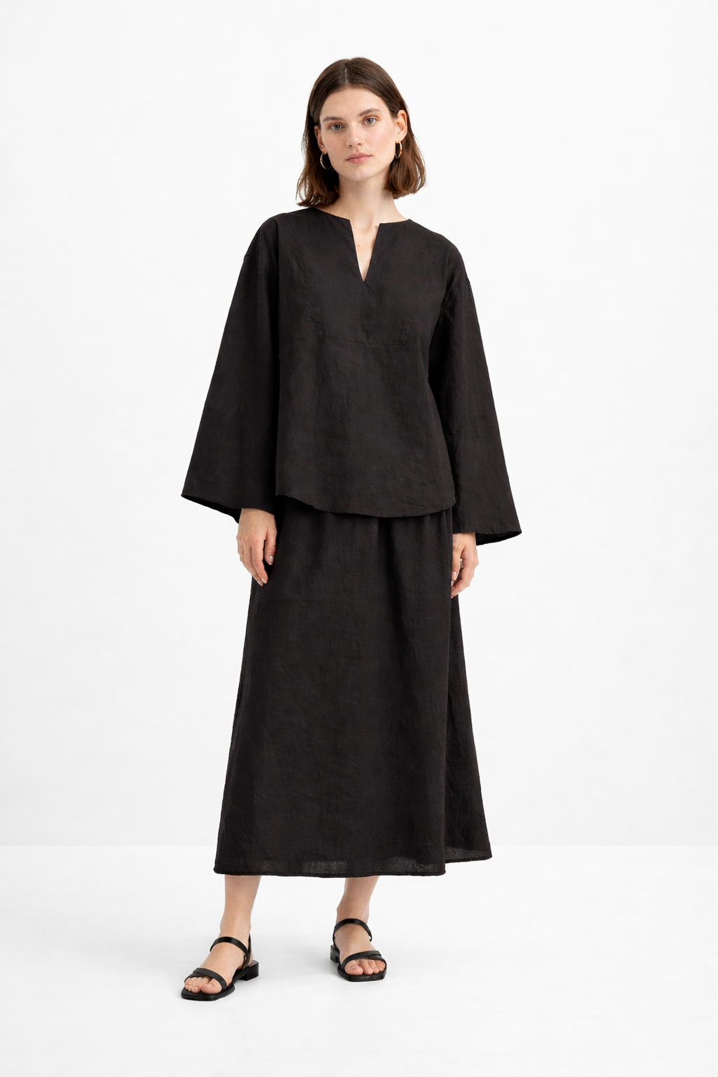 Woman wearing Eclipse Black Linen Set featuring a relaxed notch-neck linen top and flowing midi skirt in a front pose.
