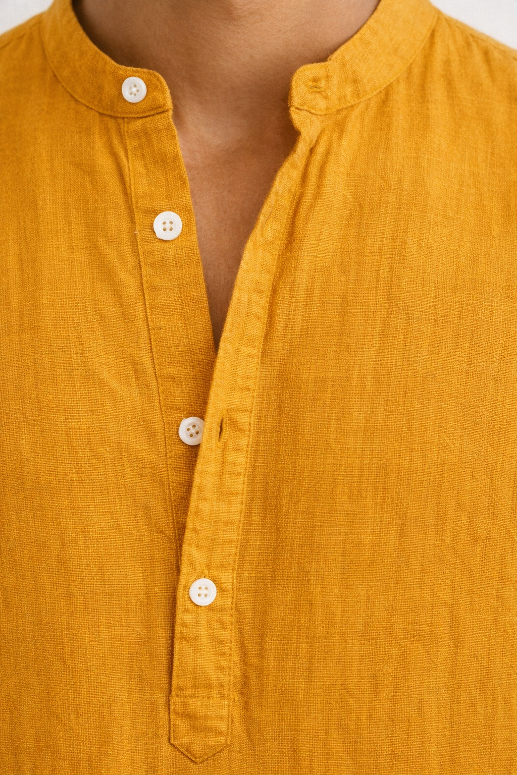 Close-up of pure linen fabric texture on mustard yellow short kurta
