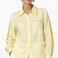 Close-up of sunshine yellow linen shirt with satin collar, pocket and sleeve detailing