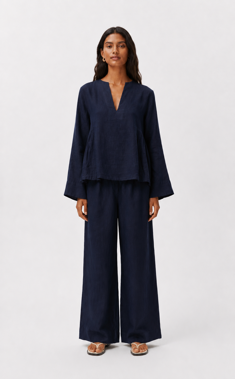 Woman wearing Twilight Navy Linen Set featuring a relaxed V-neck linen top and wide-leg trousers in pure navy linen.